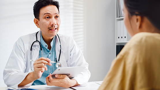 a doctor sitting at a desk discussing things with a patient